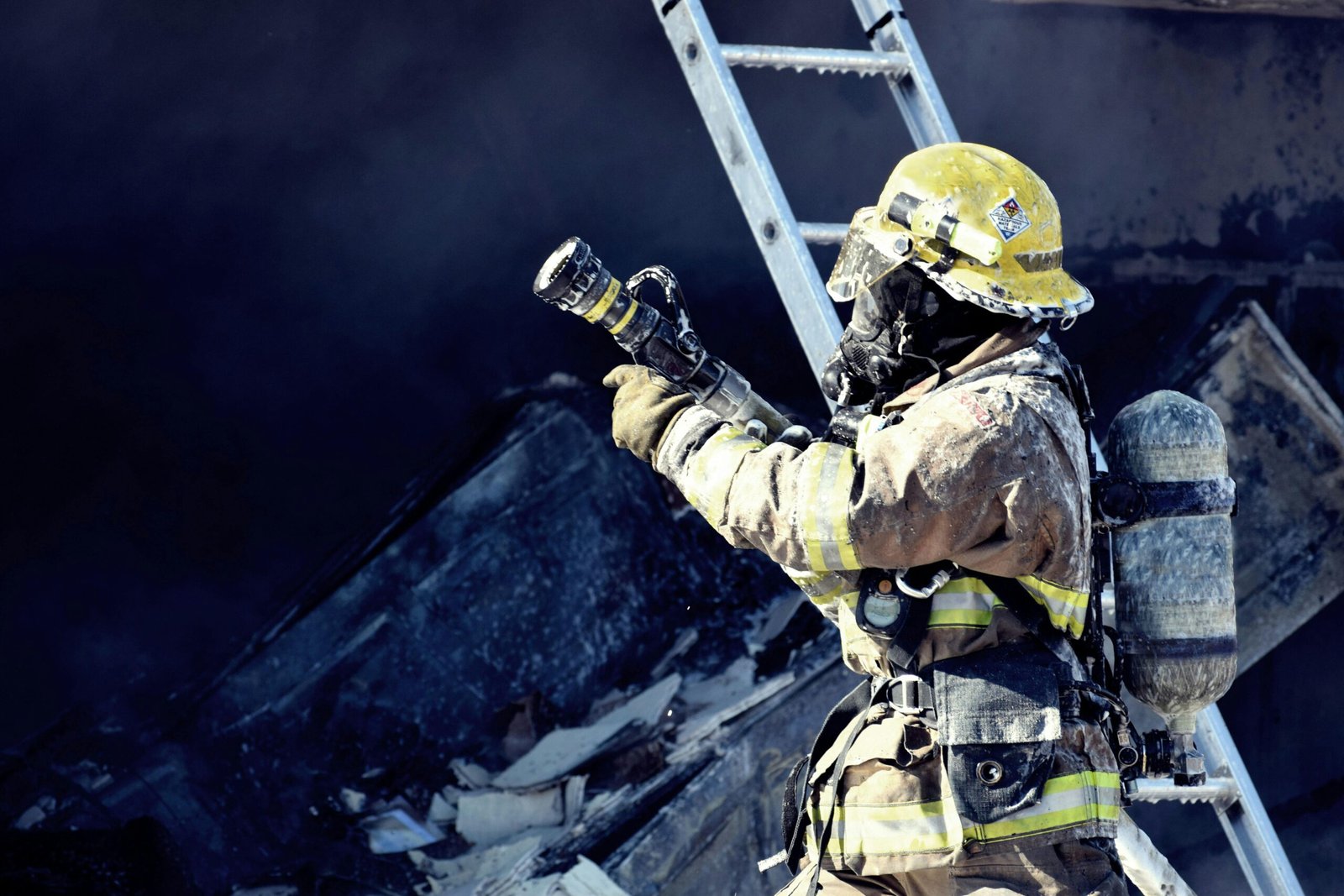 A firefighter in full gear fighting a fire with a hose, emphasizing courage and safety.
