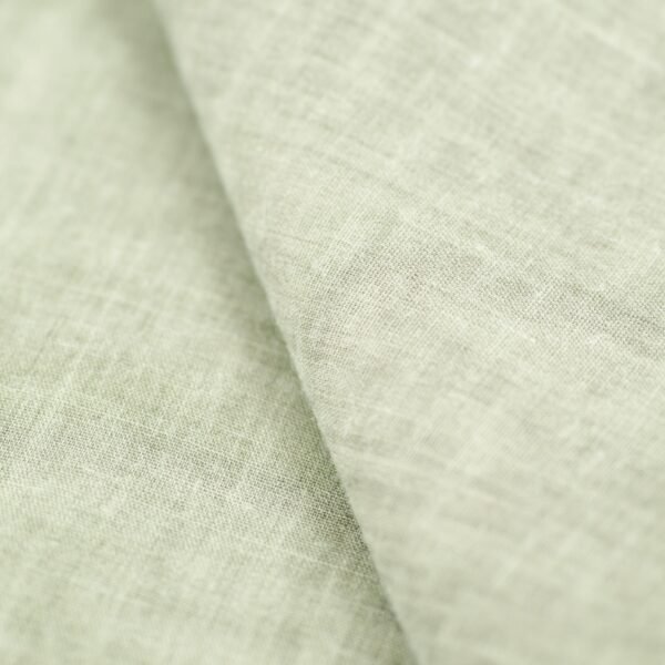 A close-up view of a soft, light-colored linen fabric displaying its intricate texture and weave.