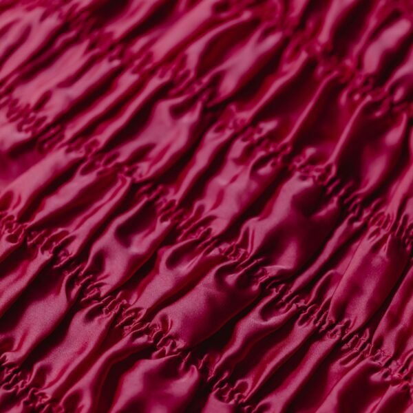 Close-up of vibrant magenta satin fabric showcasing its silky texture and rich color.