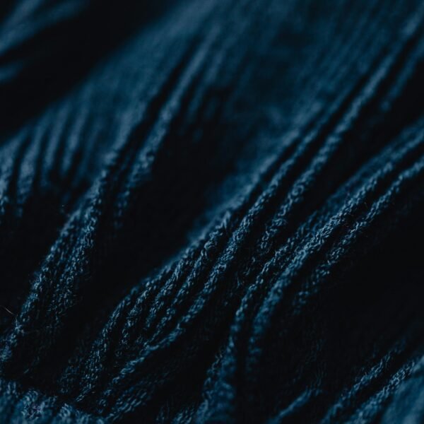 Detailed close-up image of dark blue knitted fabric showcasing its intricate texture and fibers.