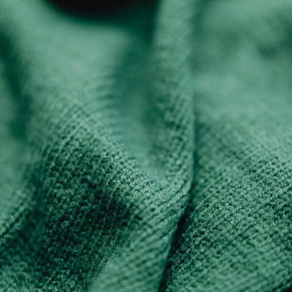 A detailed close-up of green woven fabric showcasing texture and patterns.