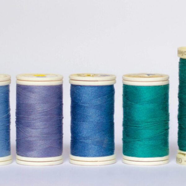 A variety of blue and green sewing thread spools arranged on a white background.